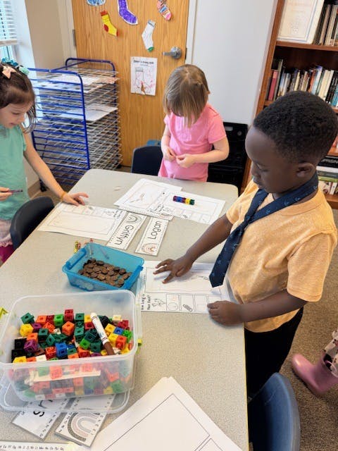 children working on an activity at a table in a classroom