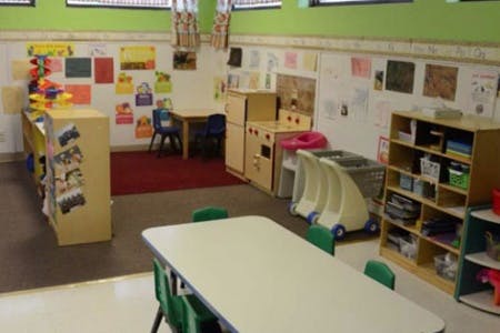 Classroom with tables, chairs, and shelves with children's artwork on the walls