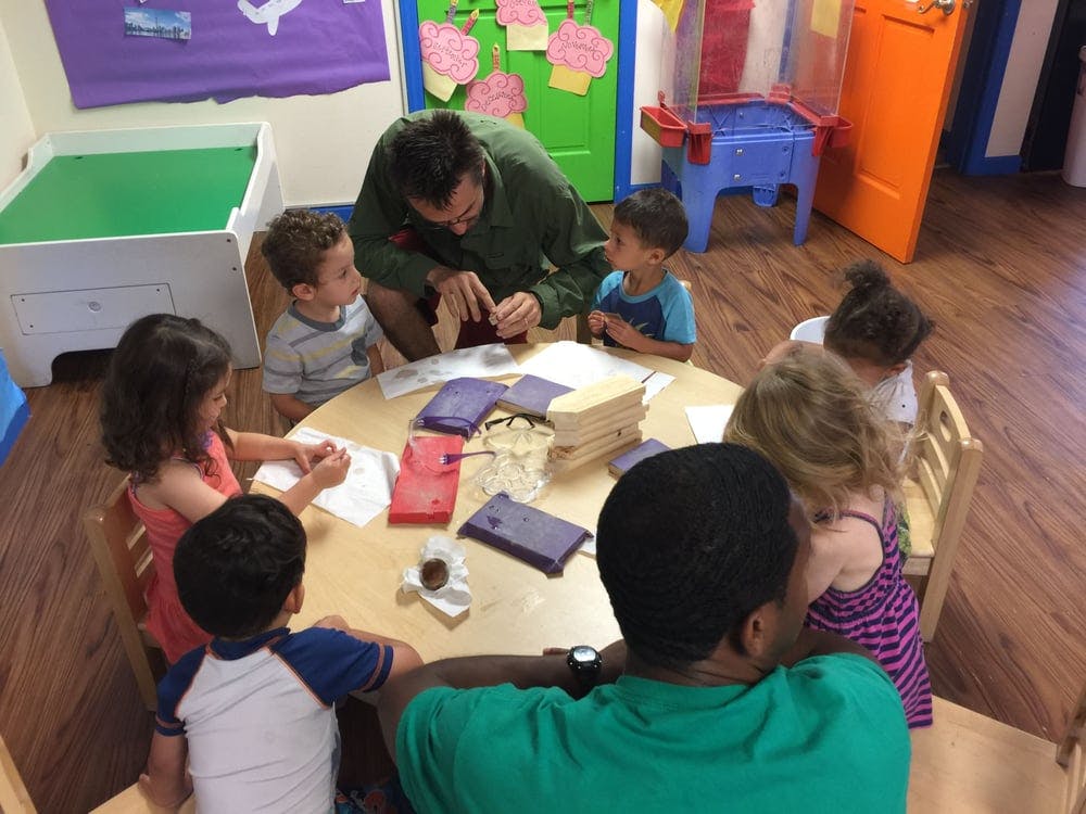 Adult and children gathered around a table in a classroom
