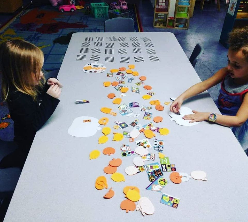 Two children playing with craft supplies on a table