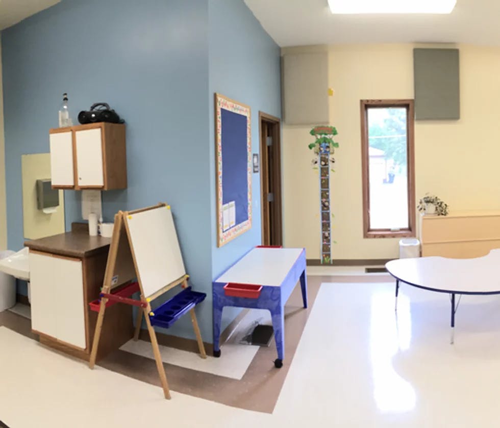Classroom with small tables, an easel, and bulletin board