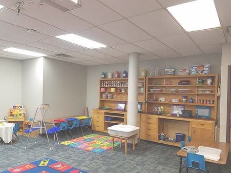 Classroom with small tables, chairs, and wooden storage units