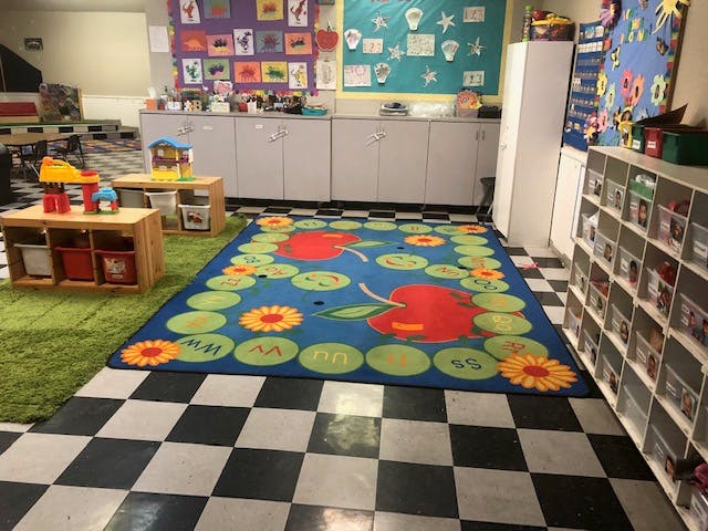 Classroom with a blue rug featuring apples and flowers