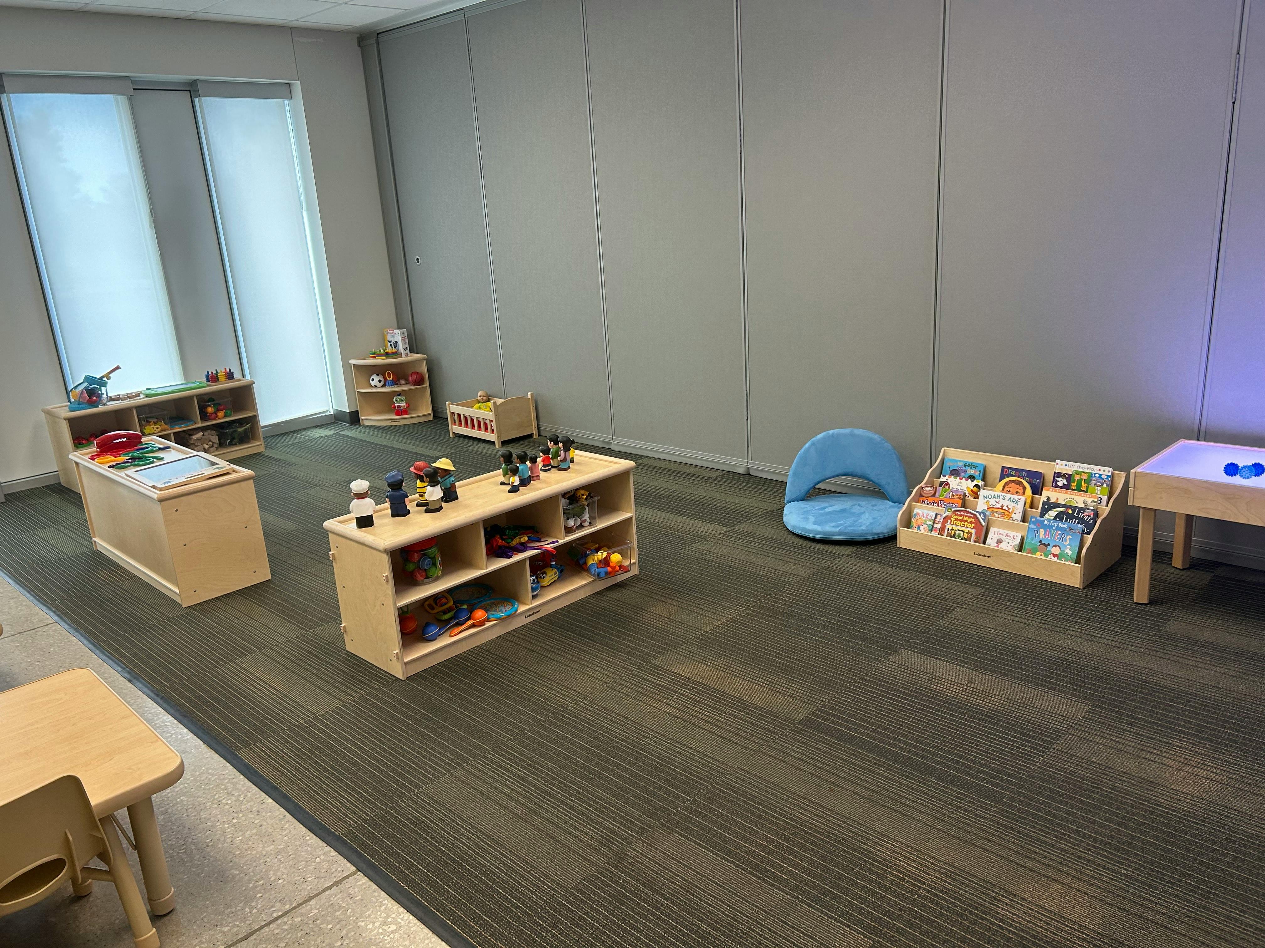 Playroom with small wooden shelves, tables, and a blue chair