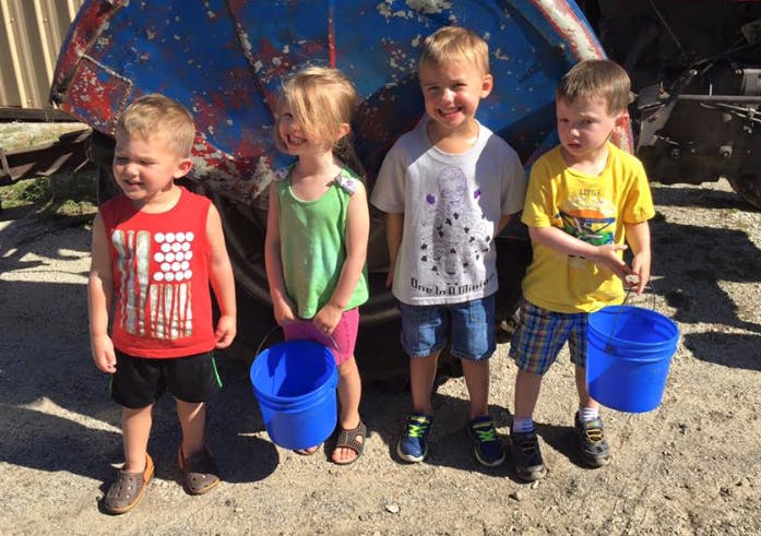 Four children standing with blue buckets