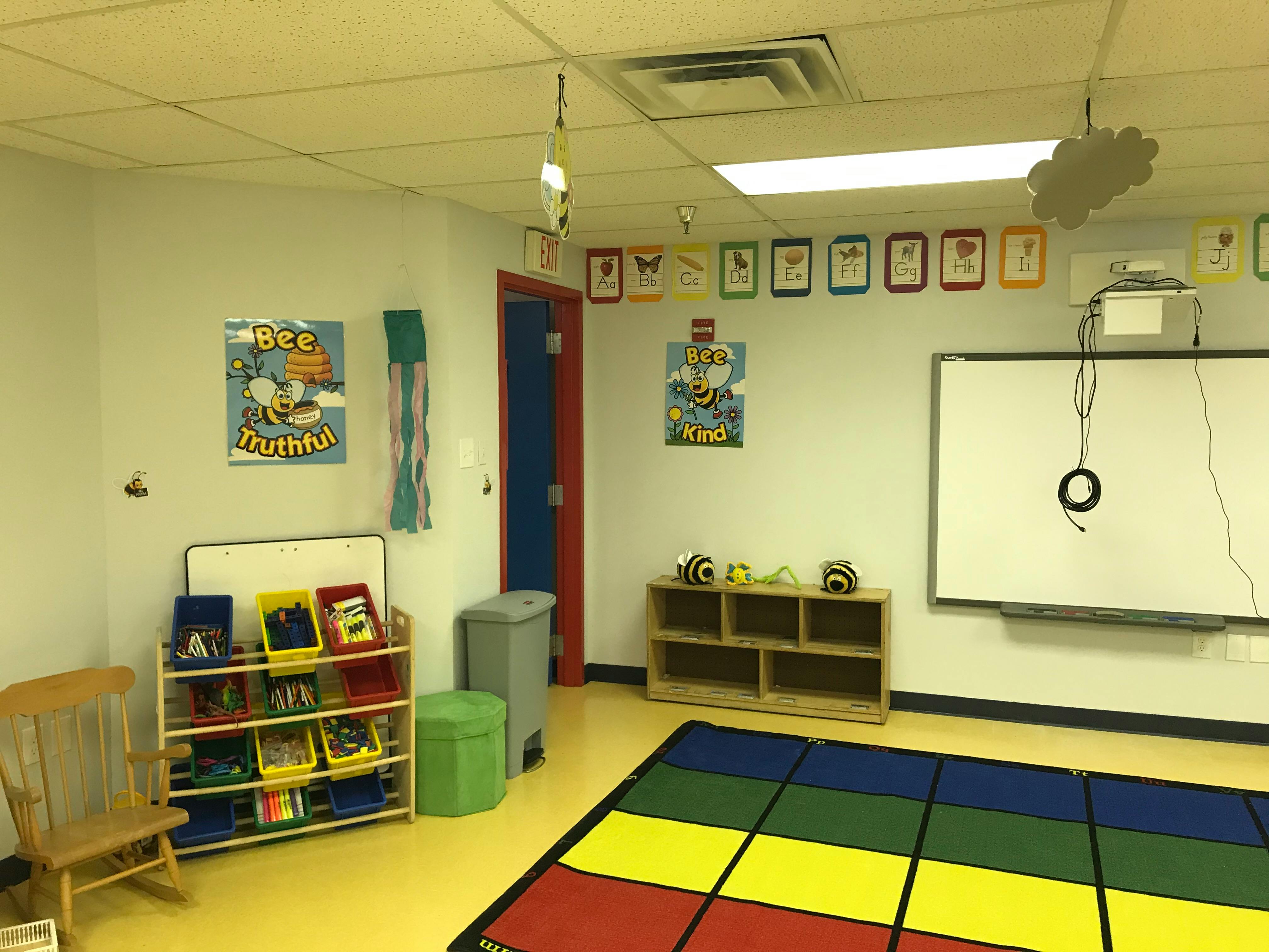 Classroom with a colorful rug, whiteboard, and shelves with books