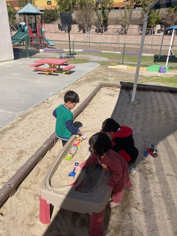 Children playing in a sandbox with toys