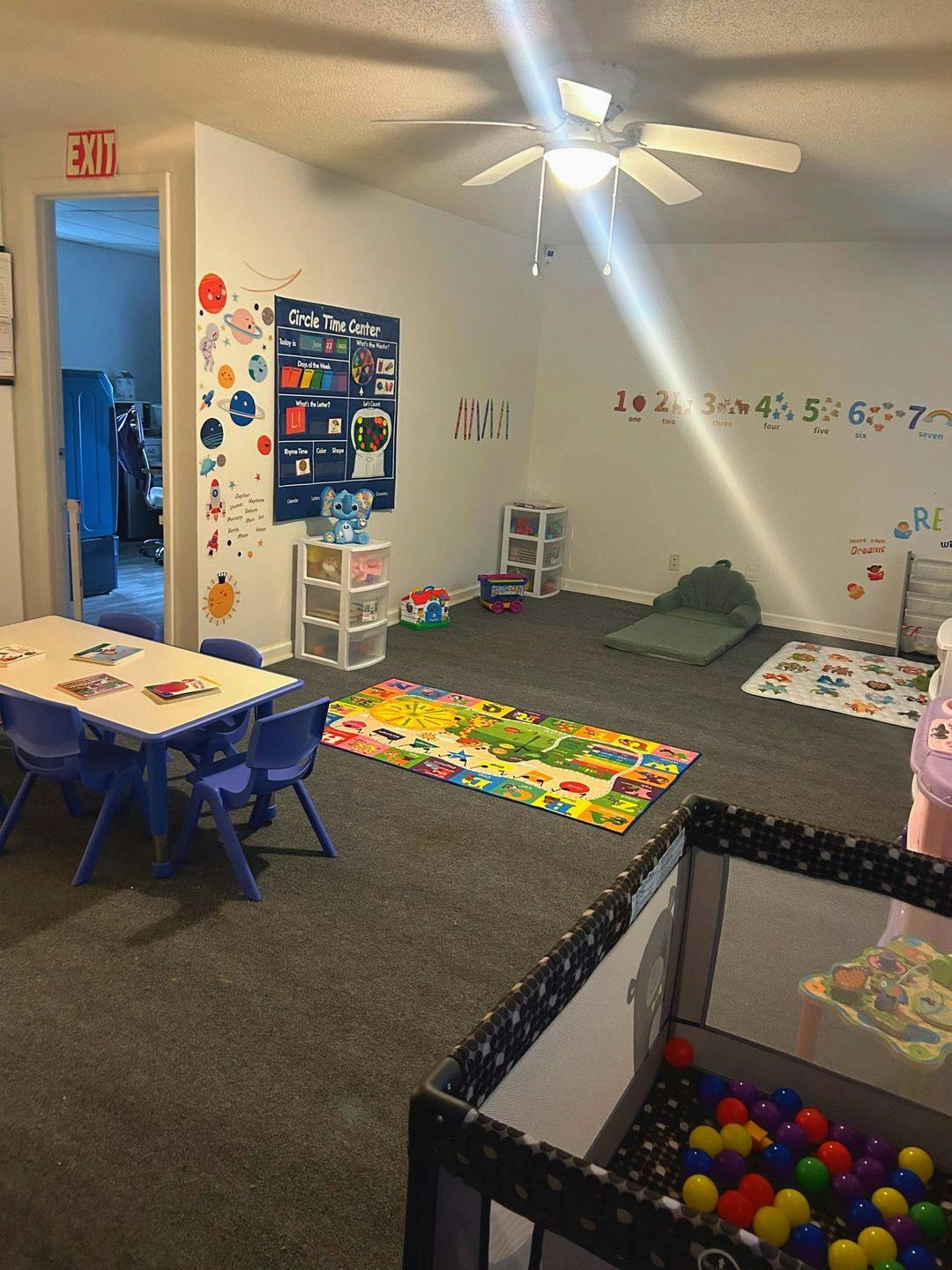 Child's playroom with small table and chairs, play mats, and a ball pit