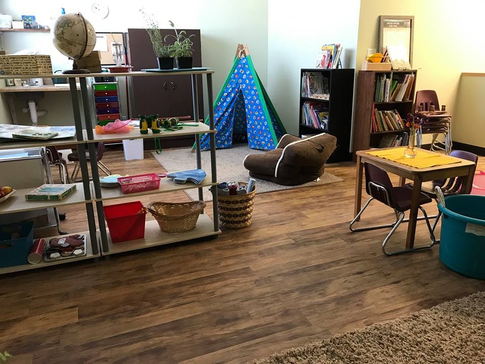 Classroom with shelves, small tables and chairs, and a play tent