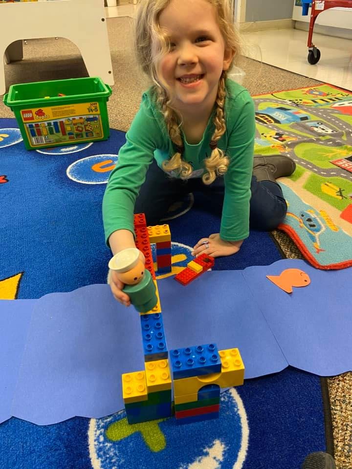 Child playing with building blocks on a blue rug