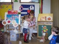 Two children and an adult interacting in a classroom setting
