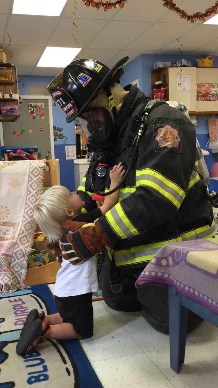 Firefighter in uniform kneeling with a child