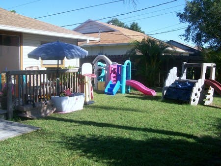 Backyard with a deck, umbrella, and colorful playground equipment