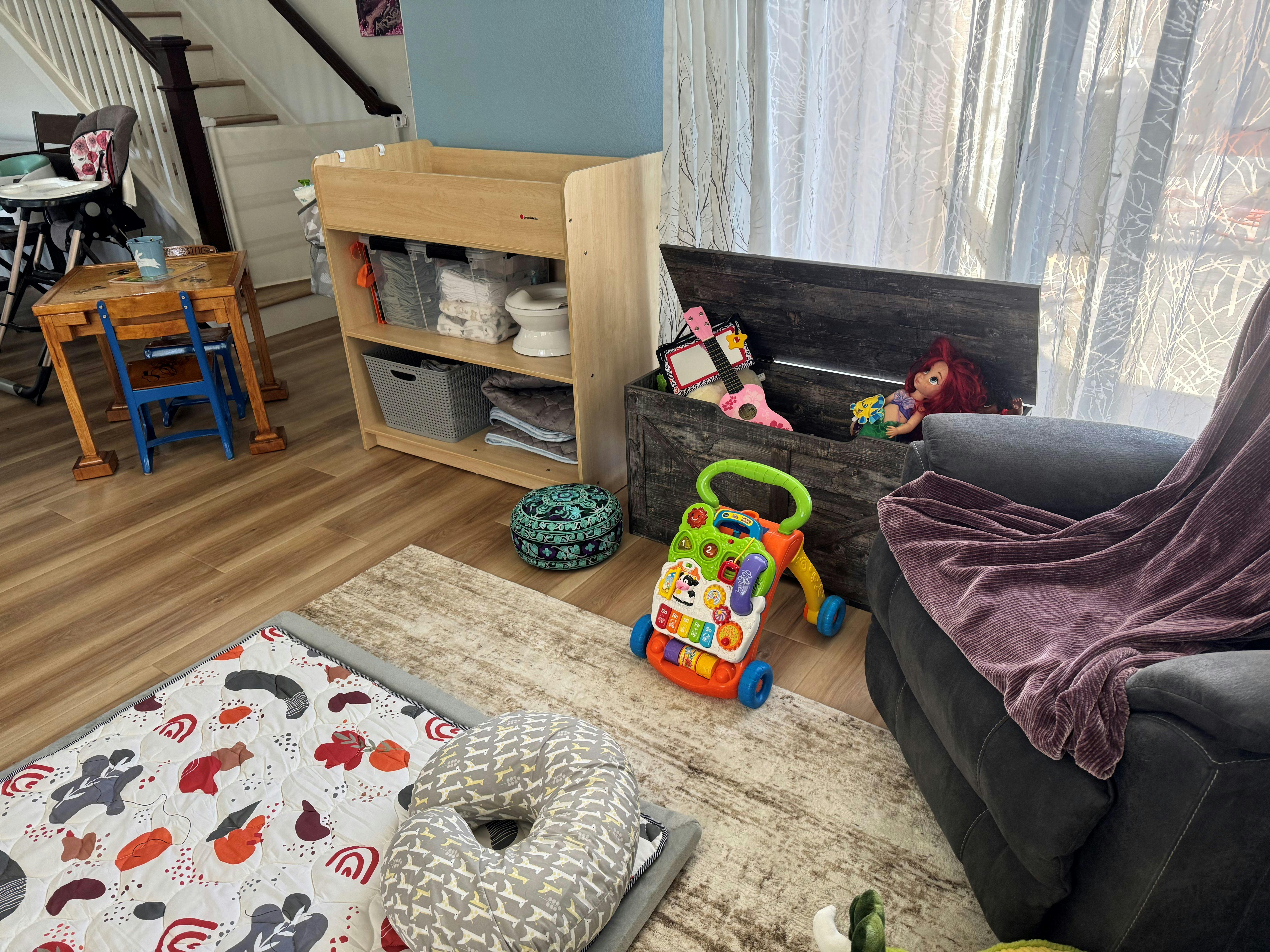 A room with baby furniture, toys, and a high chair