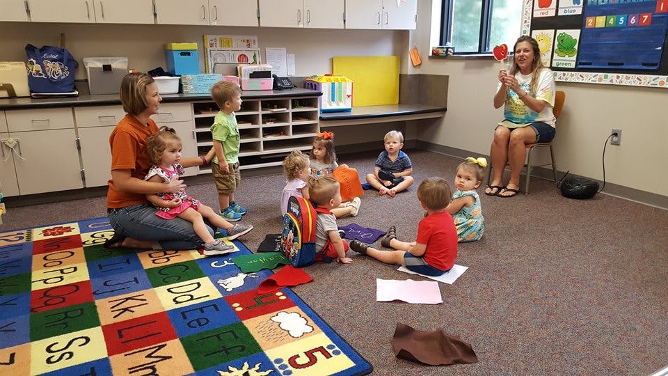 Two people with a group of children in a classroom