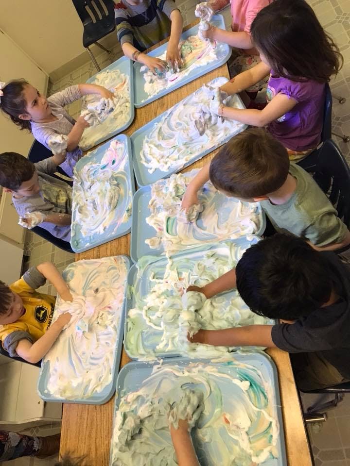 Children playing with shaving cream on trays