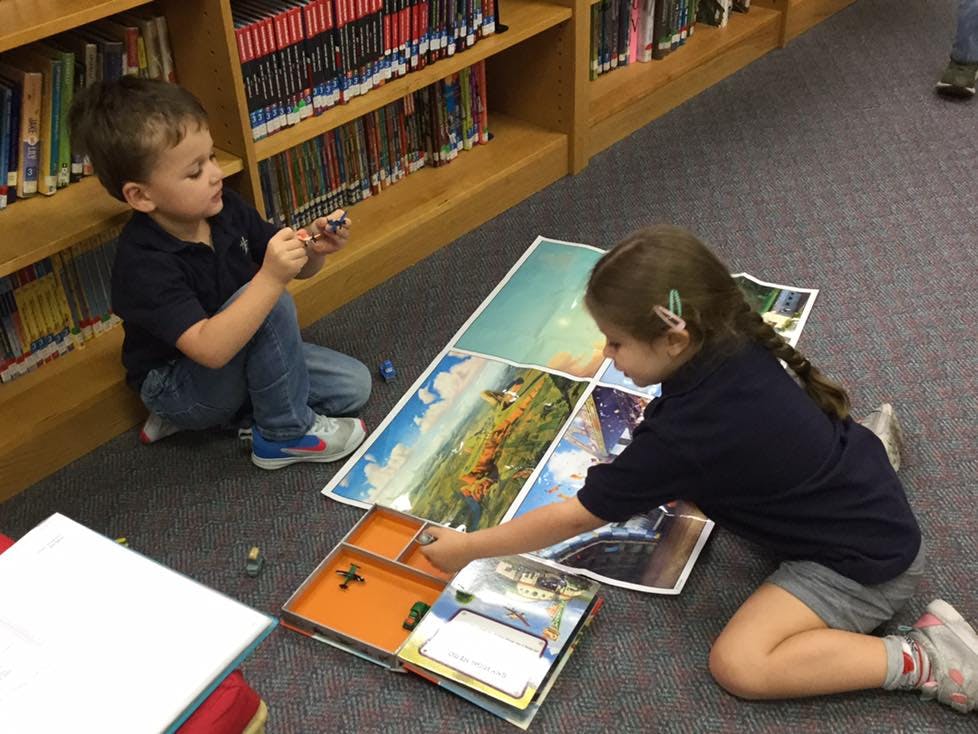 Two children playing a board game on the floor in a library