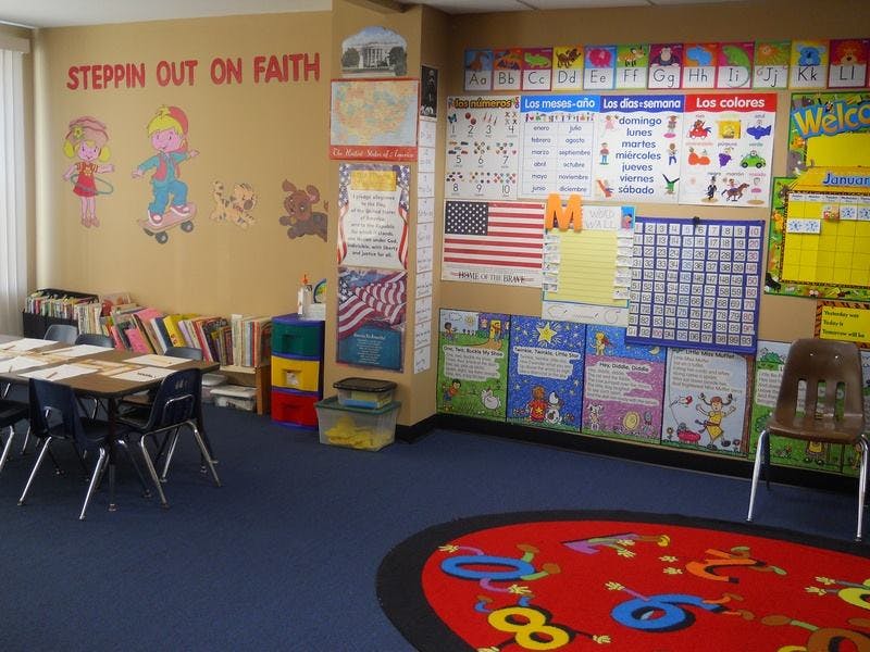 Classroom with tables, chairs, and educational posters on the walls