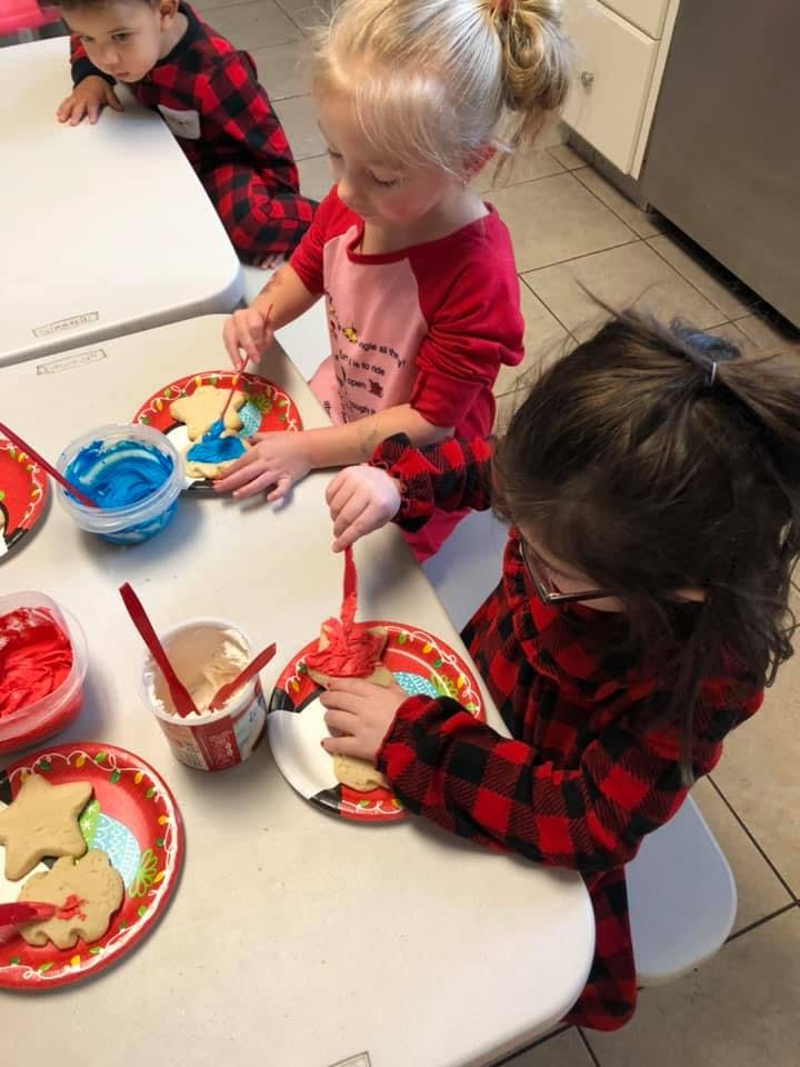 Three children decorating cookies with frosting