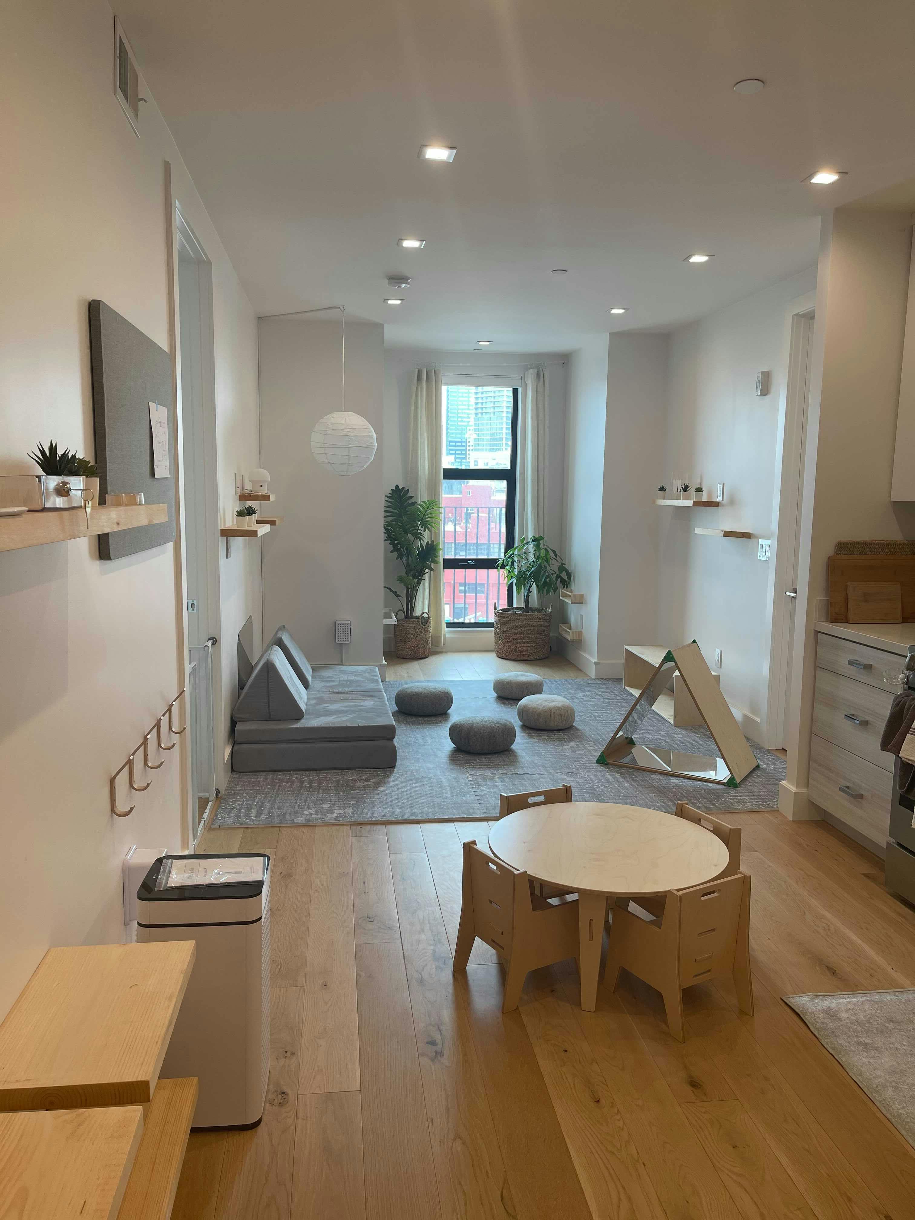 A room with a small table and chairs, a sofa, and floor cushions