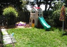 Play structure with slide and sandbox in a grassy yard