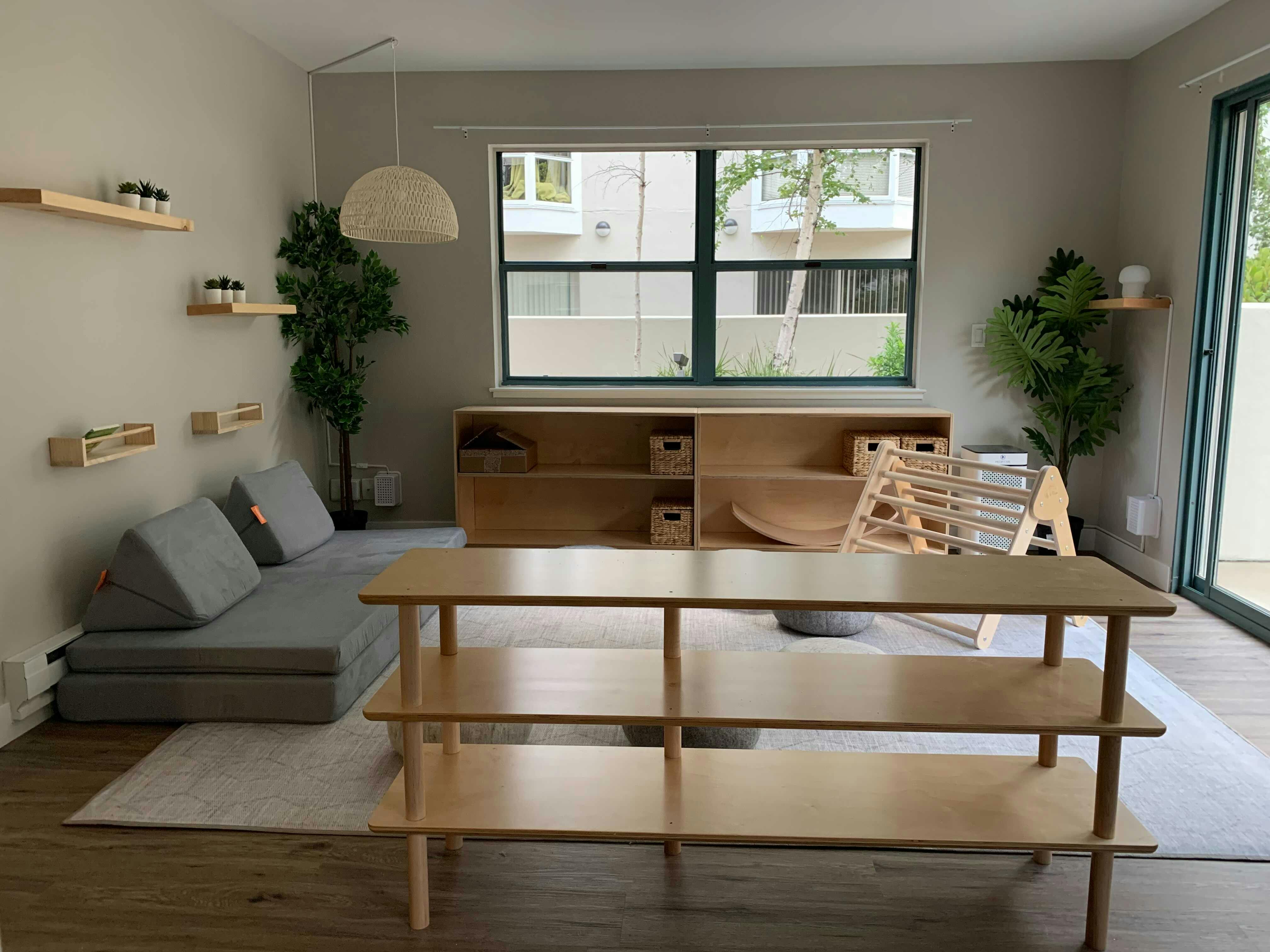 Living room with a gray sofa, wooden shelves, and a large window