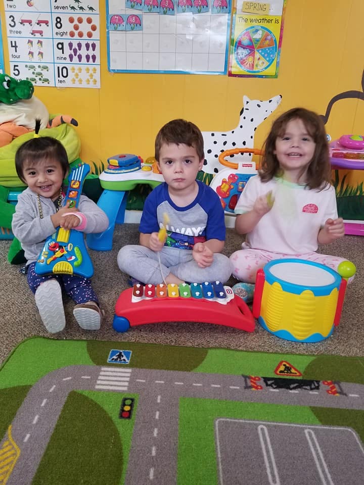 Three children playing with musical toys