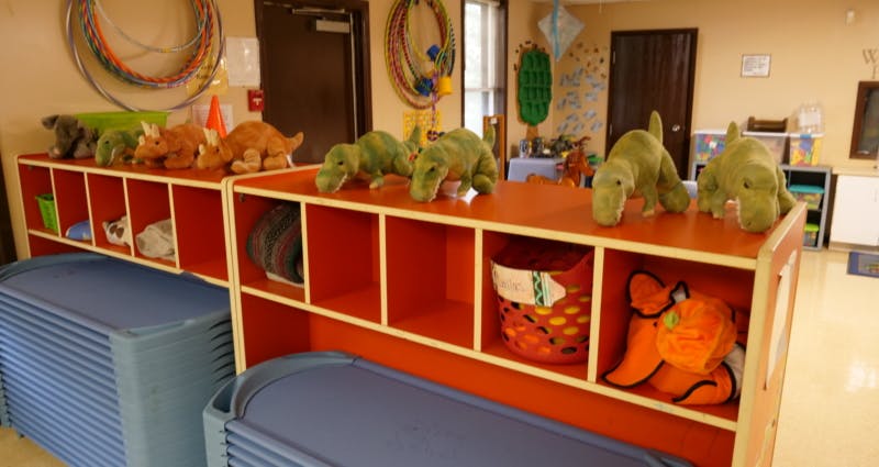 Stuffed dinosaur toys on top of red cubbies in a classroom
