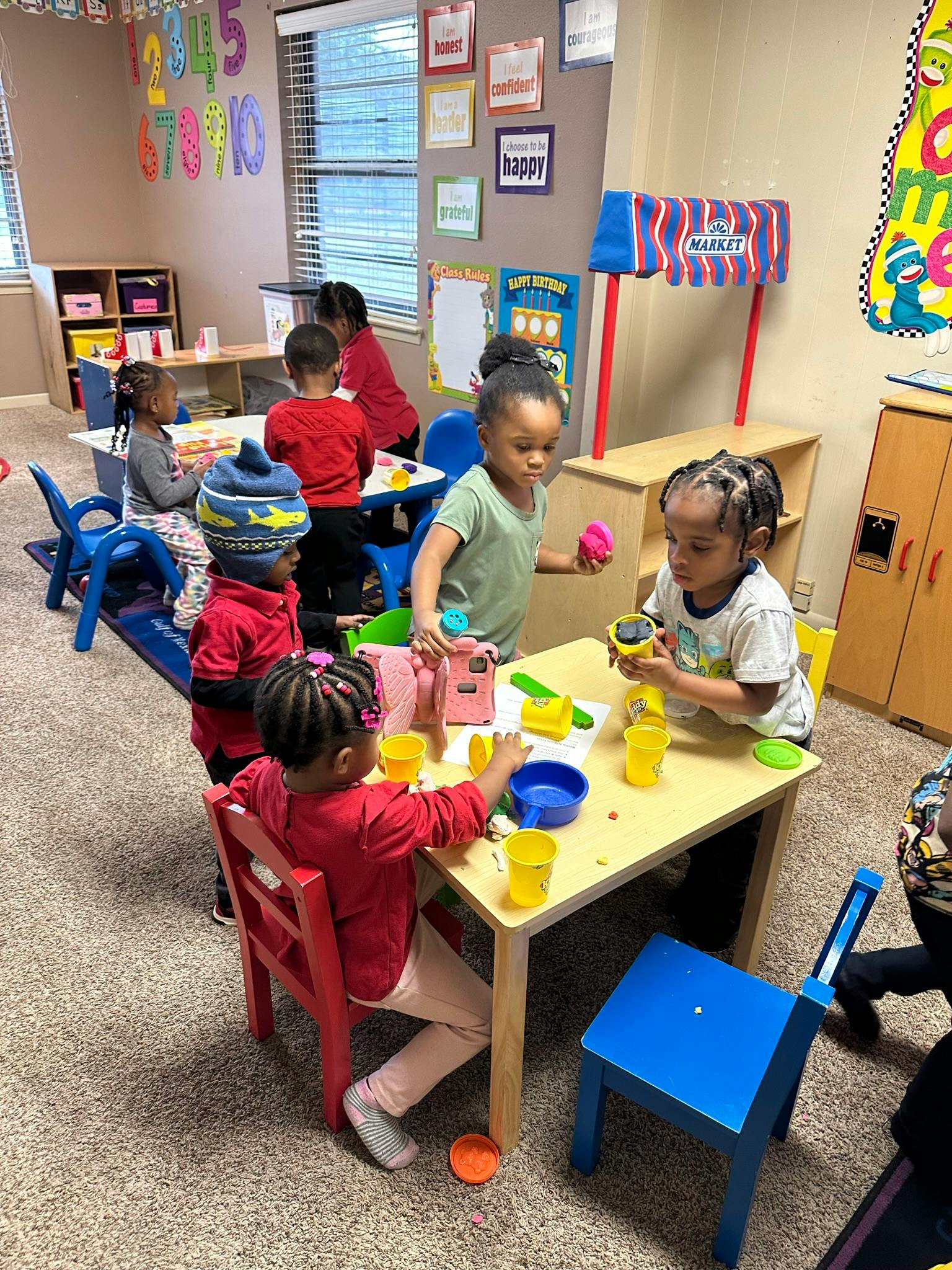 Children playing with toys at tables in a classroom