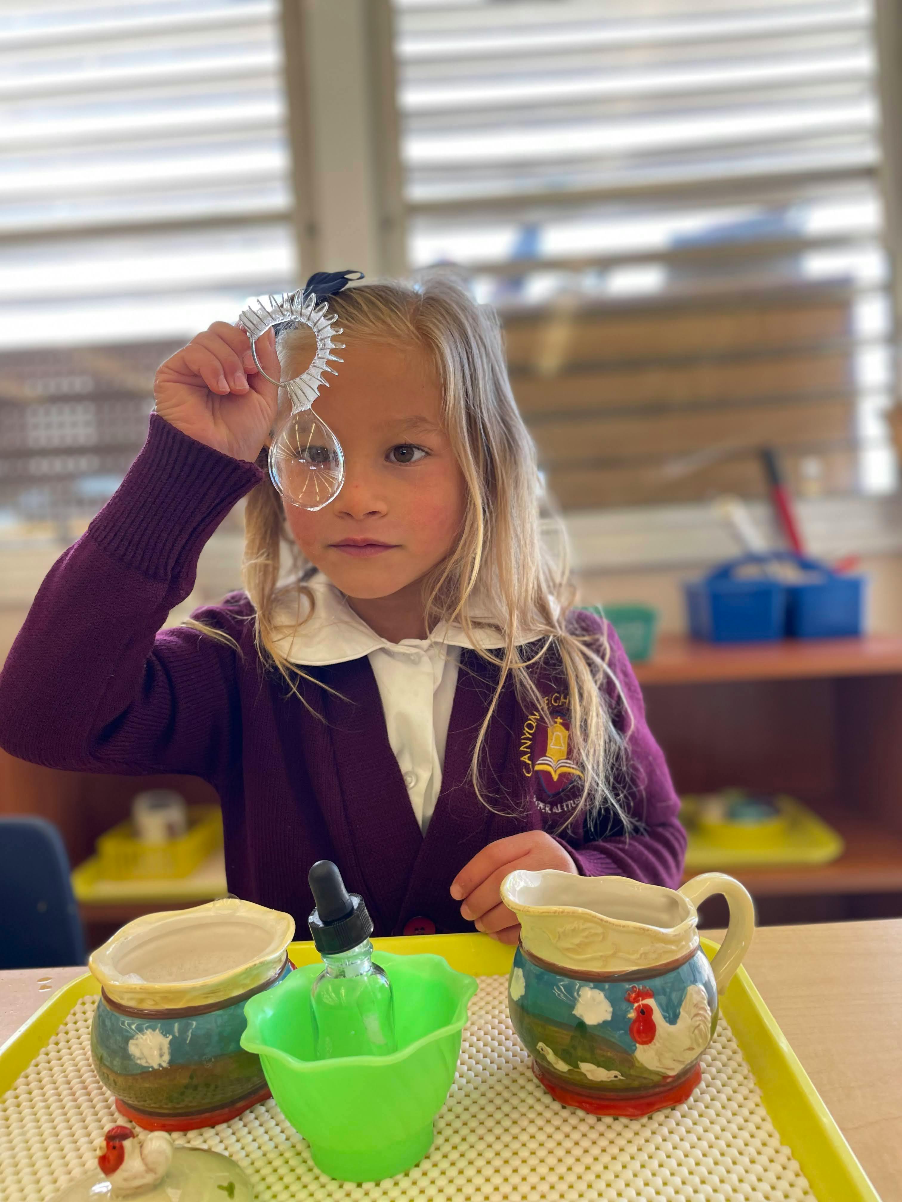 Child holding up a clear plastic object to their eye