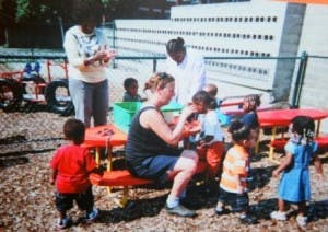 Adults and children gathered around tables outdoors