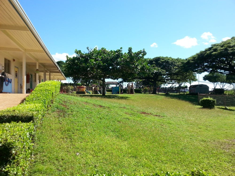 Building with covered walkway next to a grassy area with trees