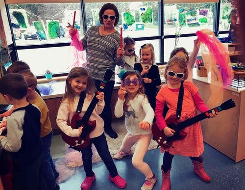 Adult and children playing with toy instruments in a classroom