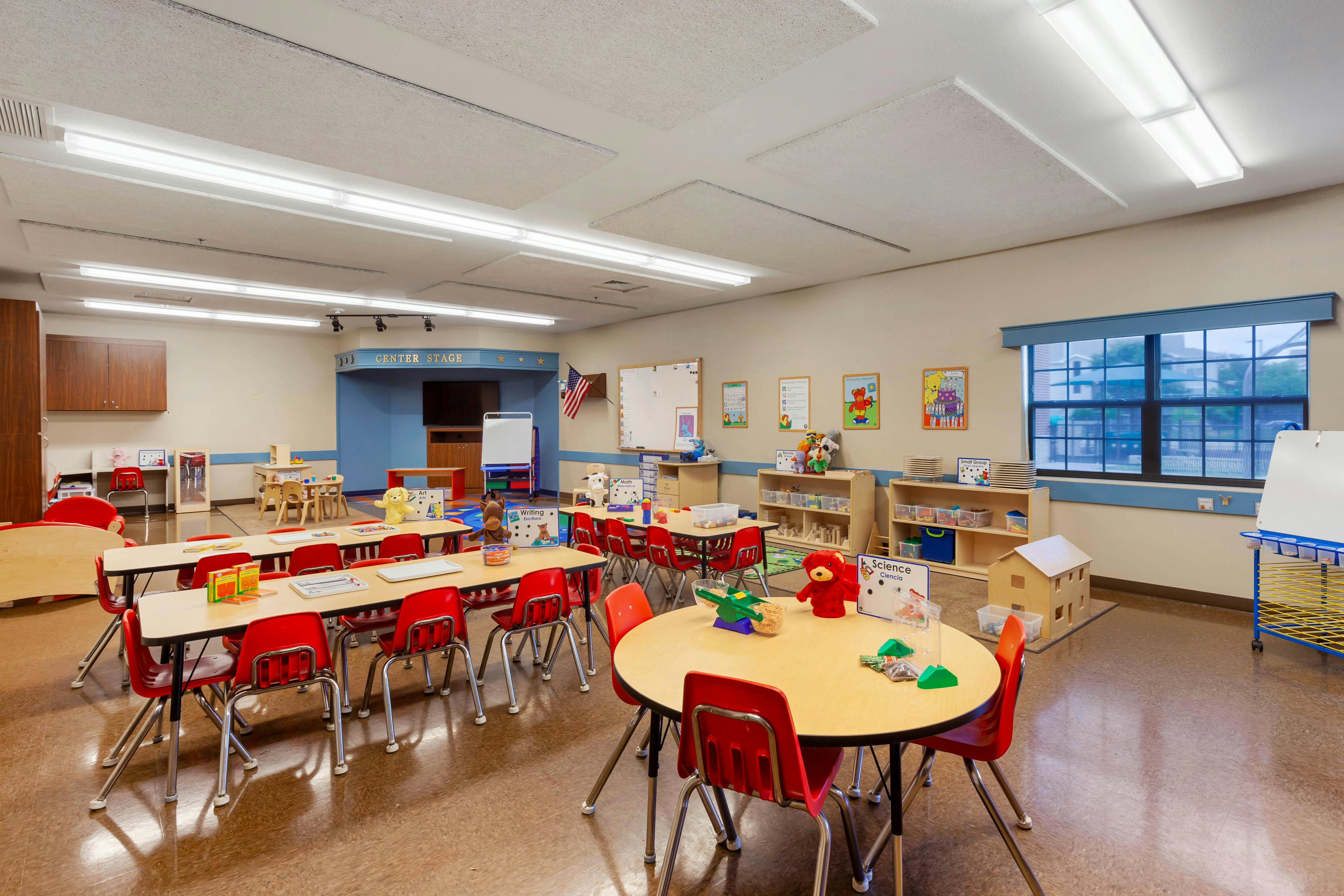 Classroom with child-sized tables and chairs, learning materials, and 'CENTER STAGE' sign