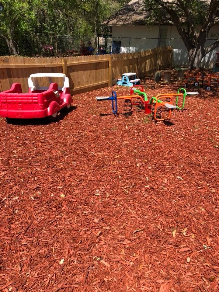 Playground with red mulch, a red toy car, and a colorful seesaw