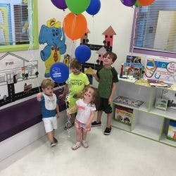 Four children standing in a room with balloons