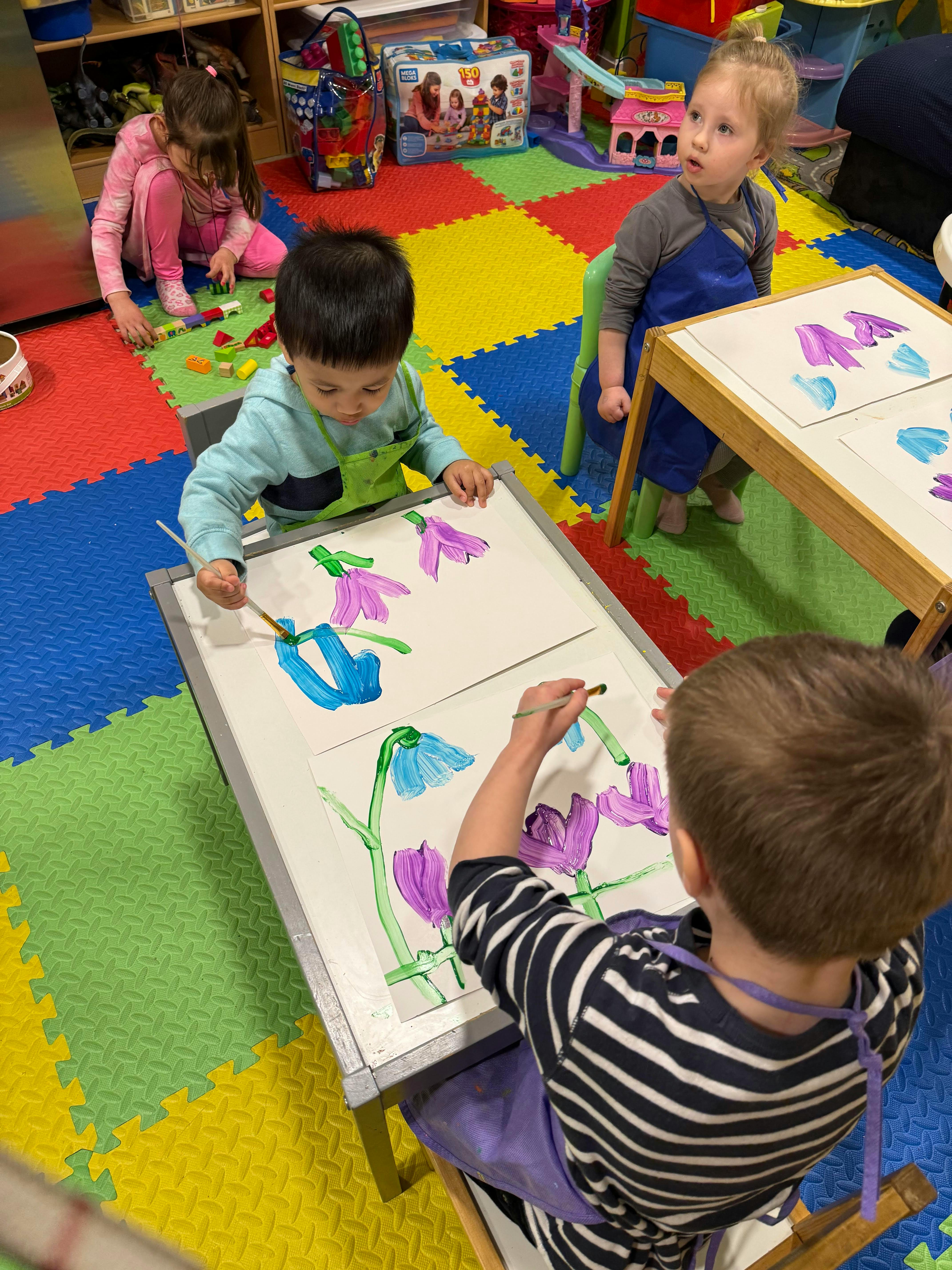 Children painting at tables in a classroom