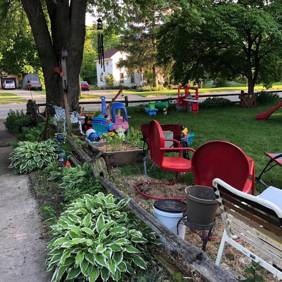 Front yard with hostas, red chairs, and children's toys