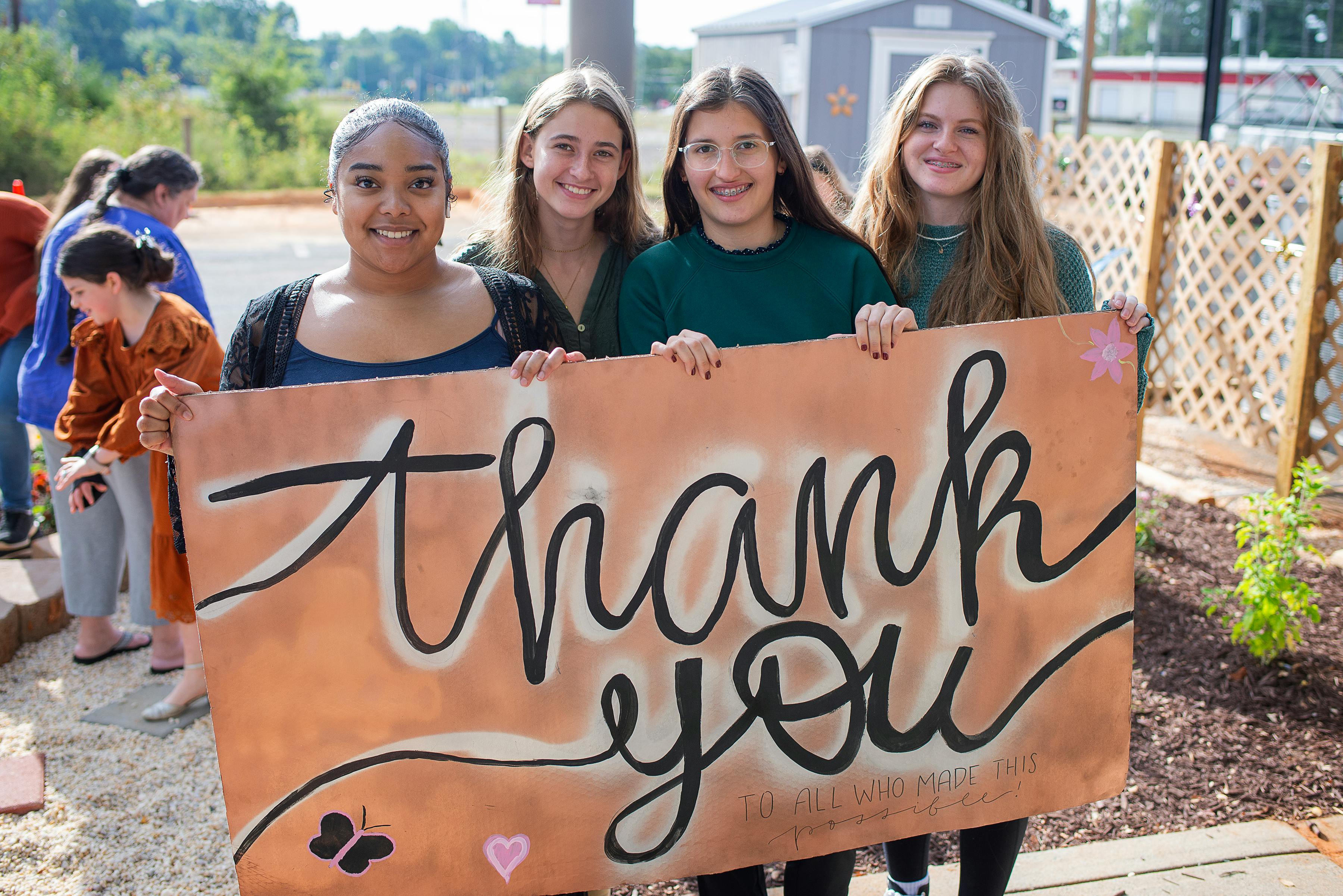 Four teens holding a "thank you" sign