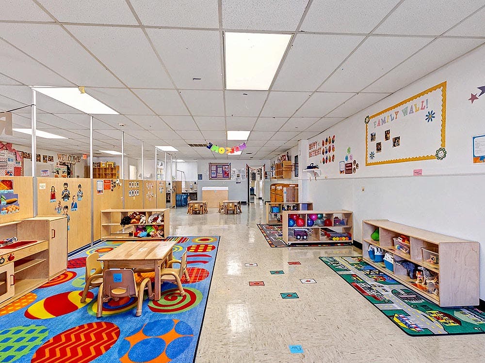 Colorful preschool classroom with tables, chairs, and play areas