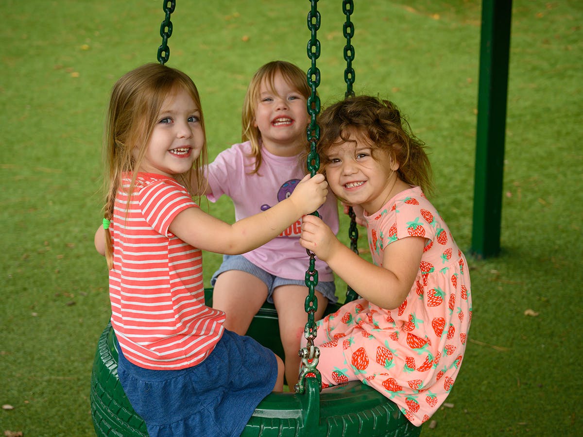 Three children on a tire swing
