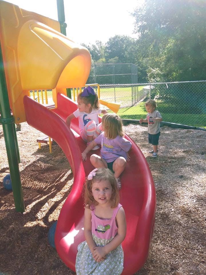 Children playing on a red and yellow slide at a playground