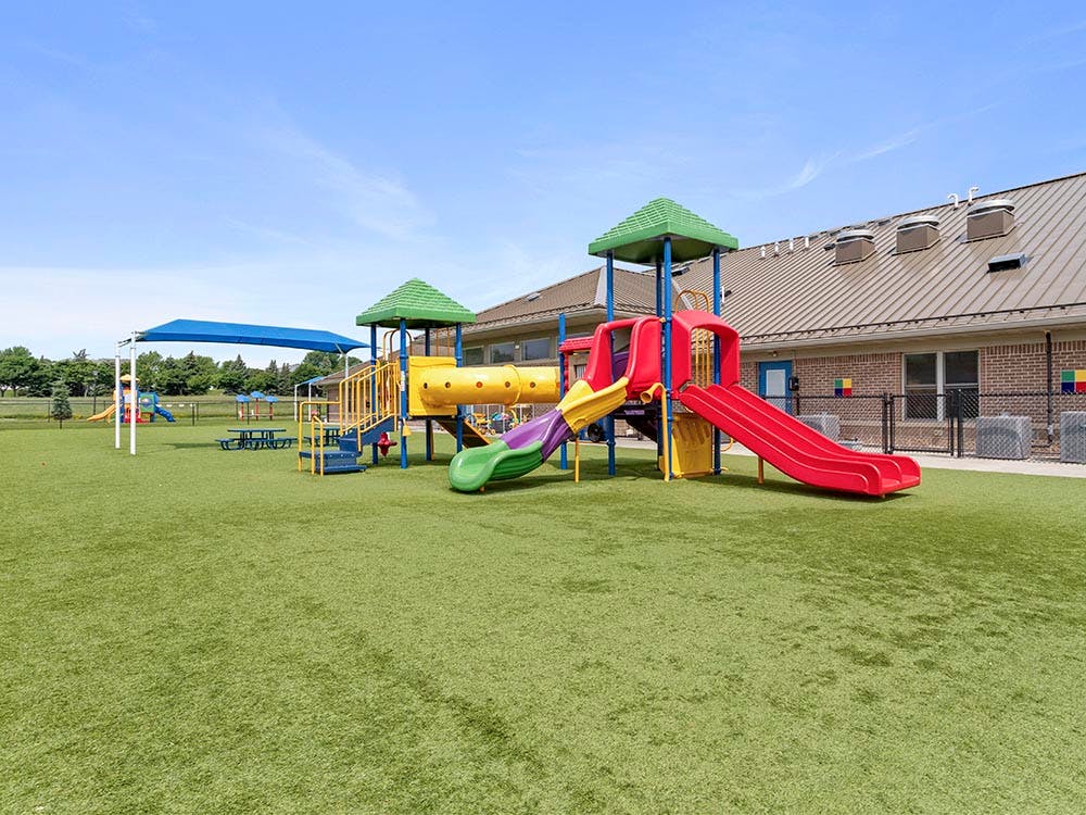 Colorful playground with slides, tunnels, and climbing structures on green turf
