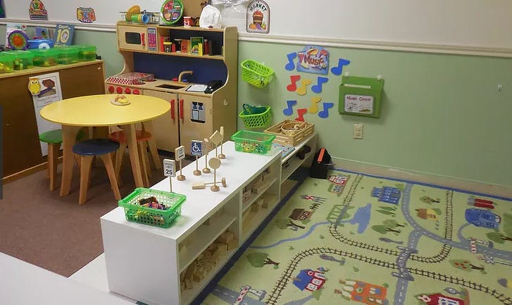 Playroom with toy kitchen, round table, and rug with a road map rug