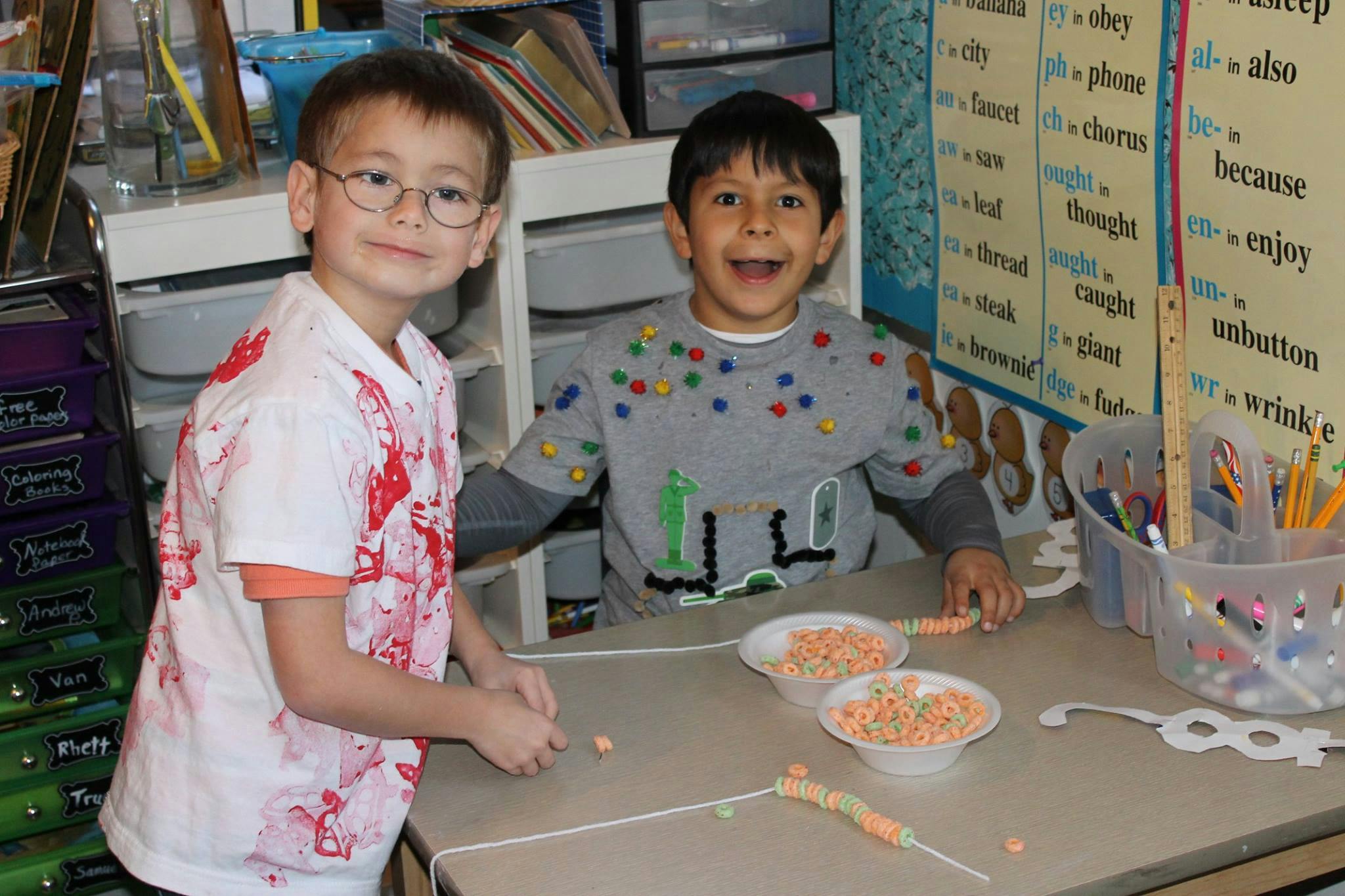 Two children at a table with bowls of cereal and crafts