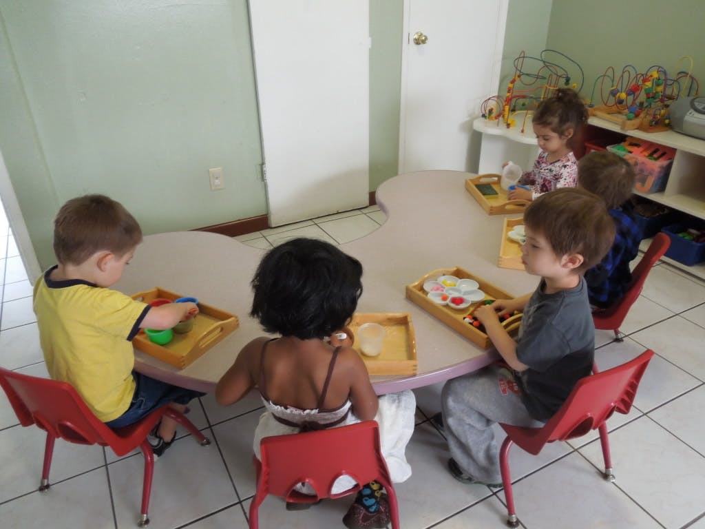 Children sitting at a table playing with toys in a classroom