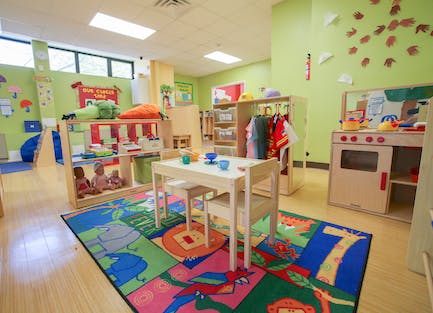 Playroom with small table and chairs, toy kitchen, and colorful rug