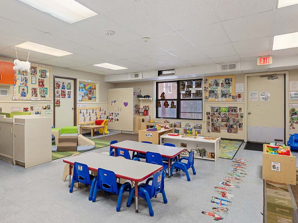 A colorful empty classroom for young children with small tables and chairs