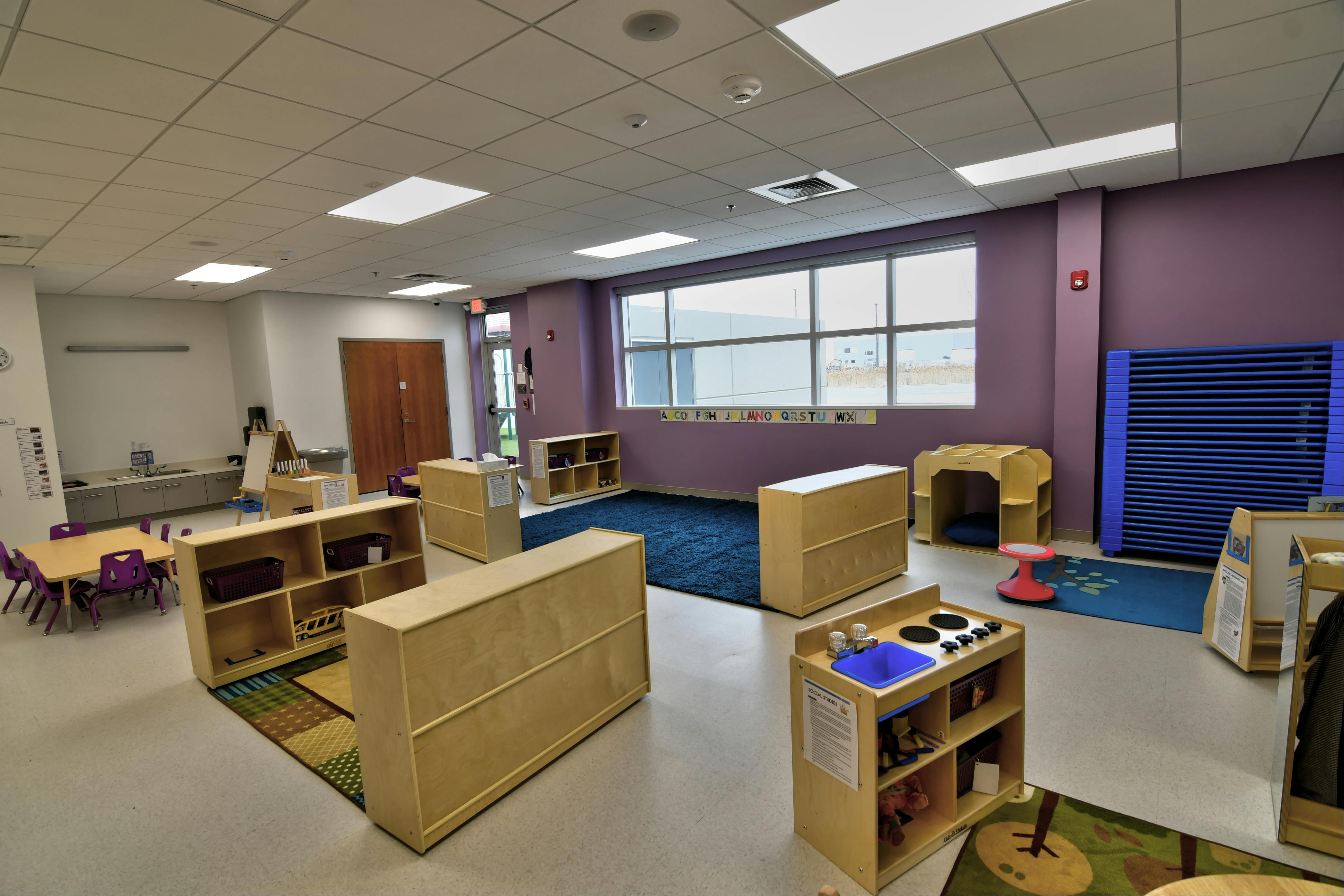 Empty classroom with small tables, chairs, and wooden storage units