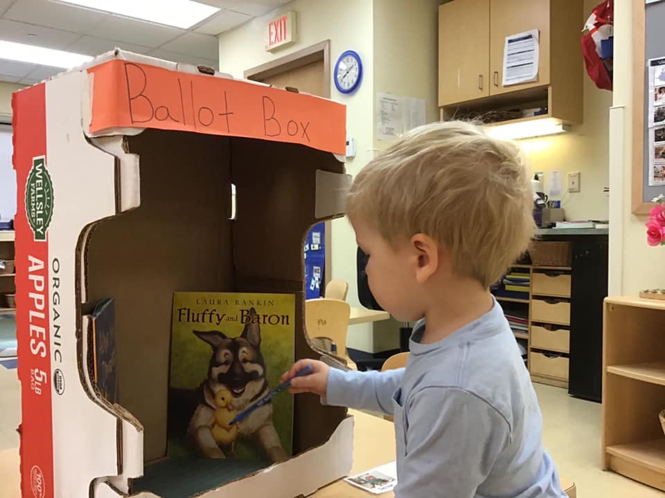 Child putting a ballot into a cardboard ballot box